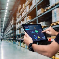 Worker hands holding tablet on blurred warehouse as background